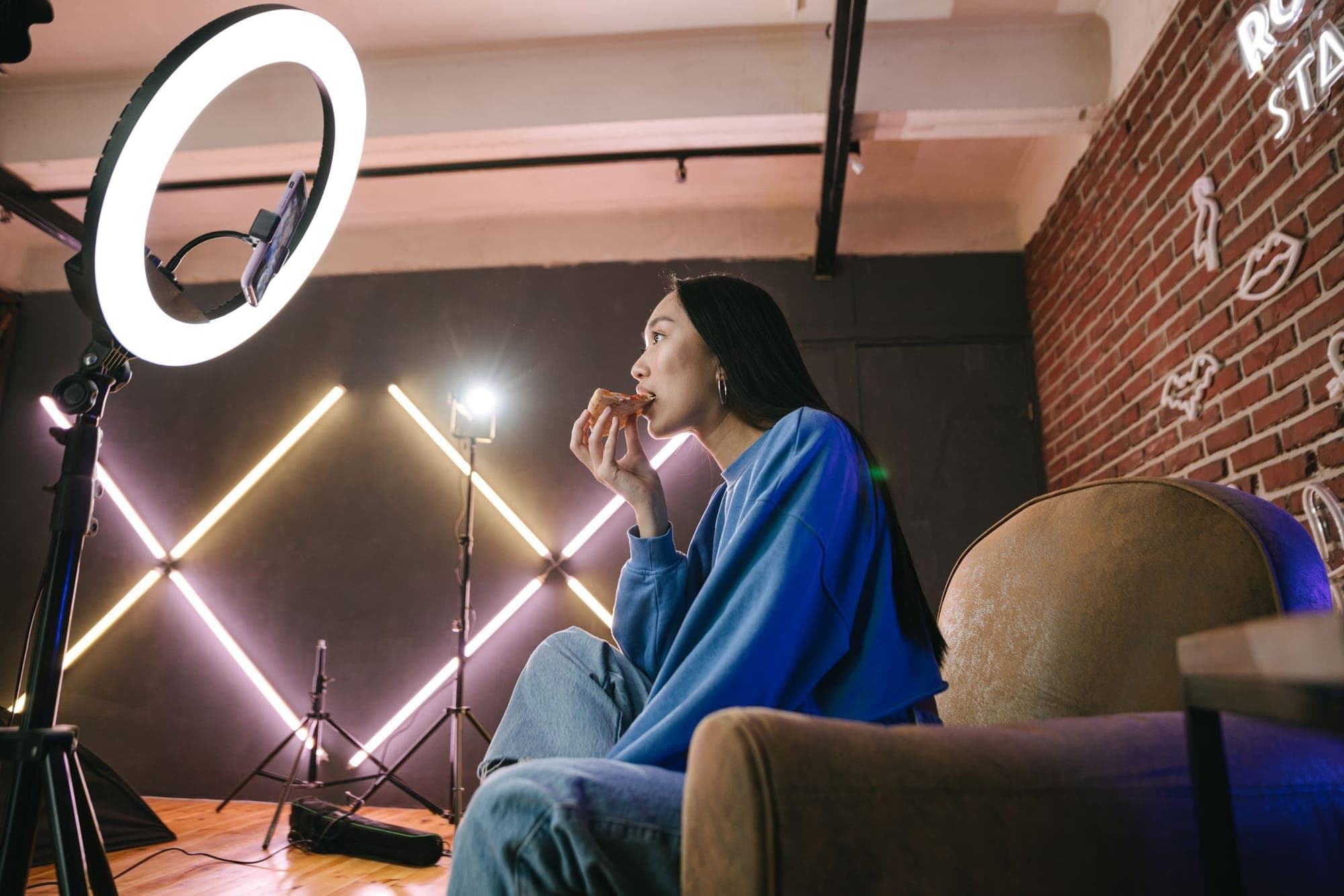 A creator sitting in a home studio with a ring light and neon strips
