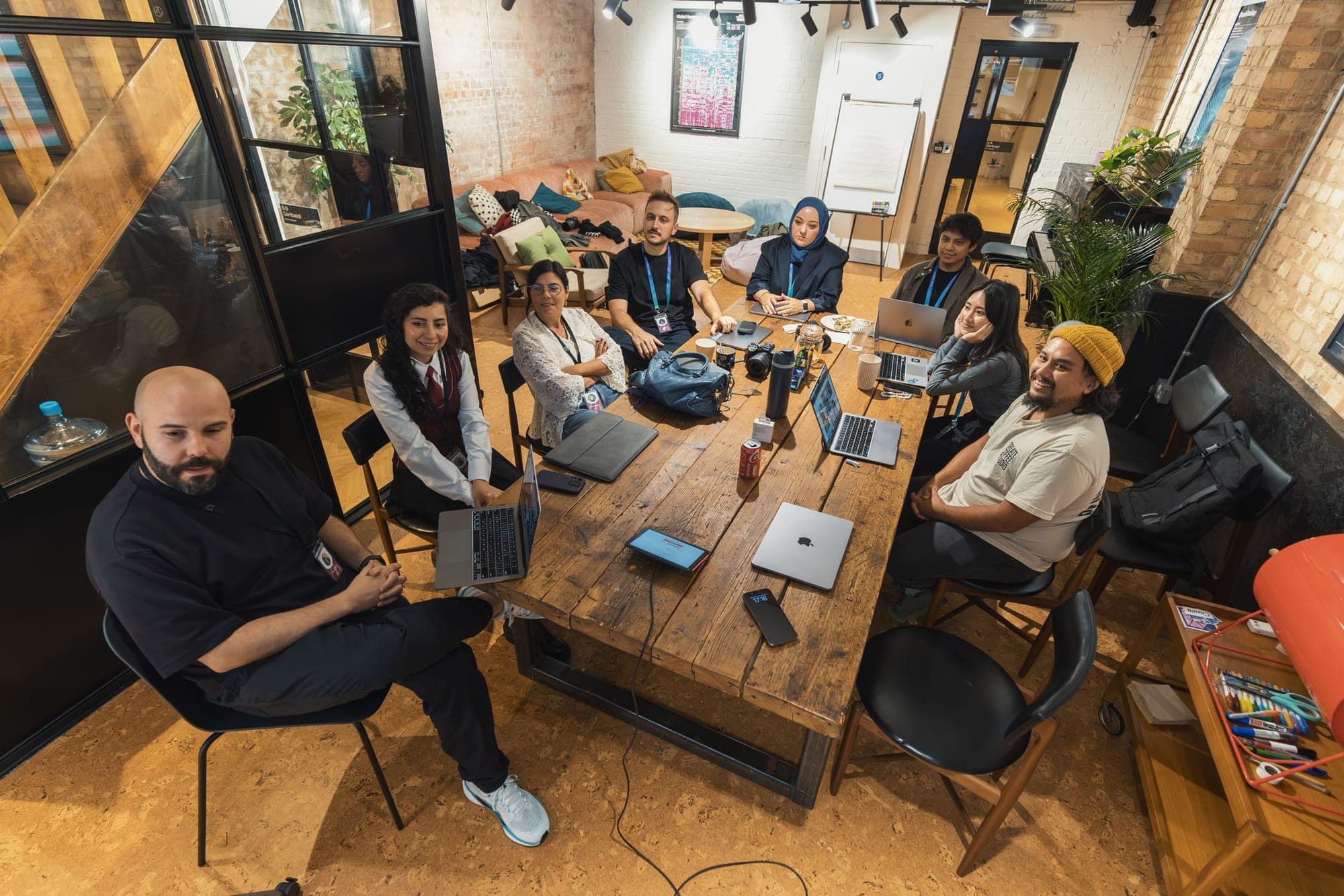 A team meeting around a long table with laptops